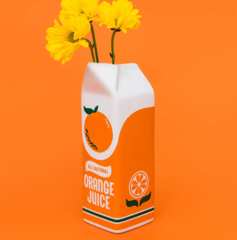 A whimsical orange juice carton ceramic vase by Ban.do with retro graphics and a watertight interior for fresh flowers.