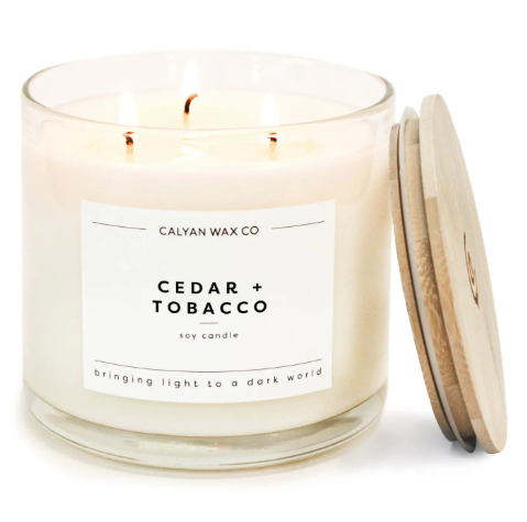 Enhance your home aesthetic with the Cedar + Tobacco 3-wick soy candle by Calyan Wax Co., featuring a clear glass tumbler and wooden lid.