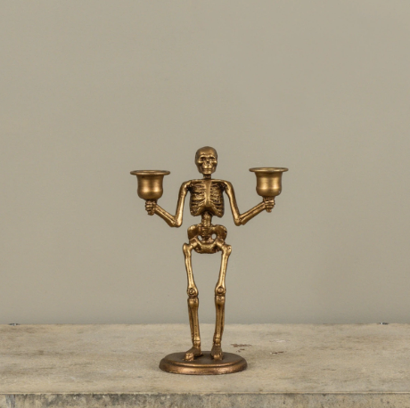 Add gothic glamour to your seasonal decor with the Gold Skeleton Taper Candle Holder by Ragon House, featuring an antique metallic finish and dual candle cups.