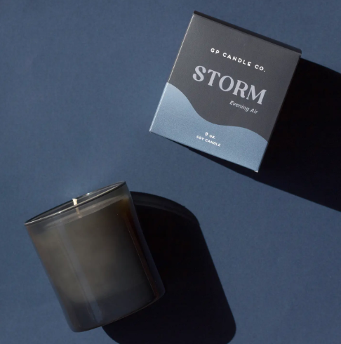 A sleek smoke-colored glass soy candle in a matching box, showcasing its moody and sophisticated packaging.