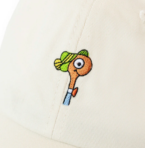 A close-up of the ivory cotton twill baseball cap, highlighting the charming Lowly Worm embroidery.