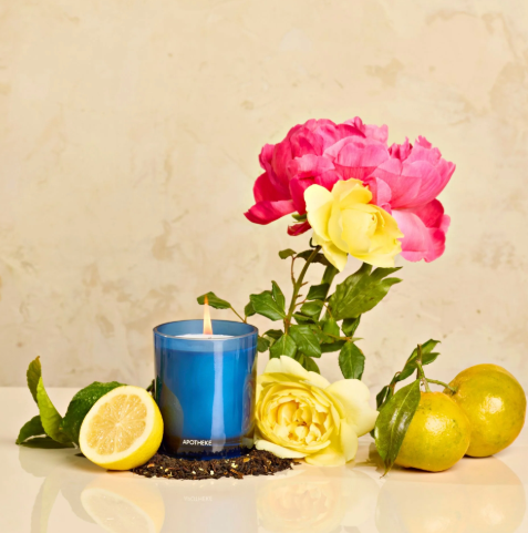 APOTHEKE Earl Grey Bitters candle, surrounded by ingredients like tea leaves, citrus fruits, and roses, reflecting its soothing and revitalizing fragrance profile.