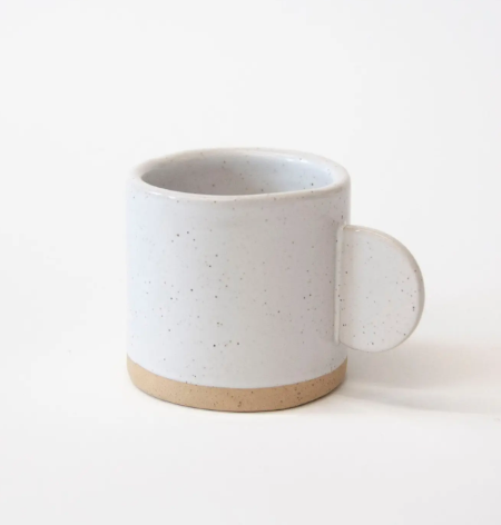 A close-up of a handcrafted ceramic espresso cup by ZWEIBIE featuring a clean white finish and sophisticated speckle detail.