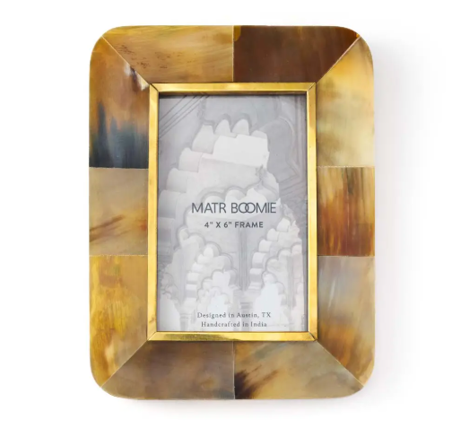 A rectangular picture frame with rounded corners, made from light and dark patterned horn with a thin brass border around the photo window.