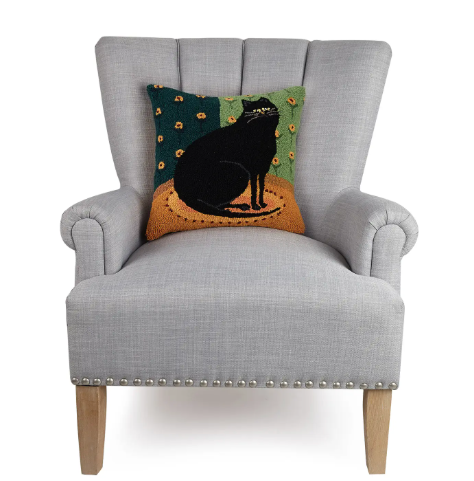Folk art inspired black cat pillow that adds a cozy and artistic touch to any living room sofa.