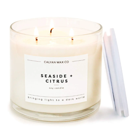 Calyan Wax Co.'s Seaside + Citrus 3-Wick Soy Candle with a wooden lid, delivering a bright, refreshing scent and supporting the fight against human trafficking.