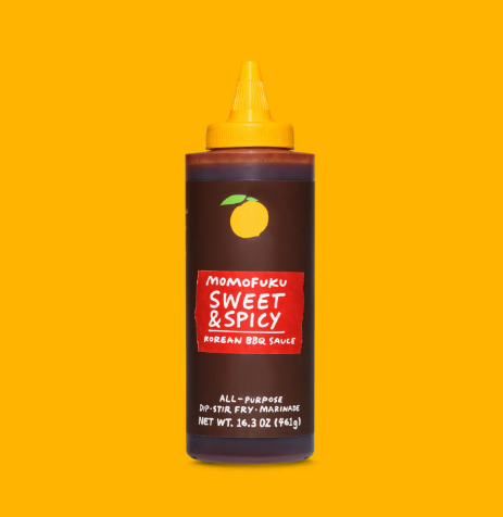 The brown squeezable bottle of Sweet & Spicy Korean BBQ Sauce by Momofuku, distinguished by its bold red label branding.