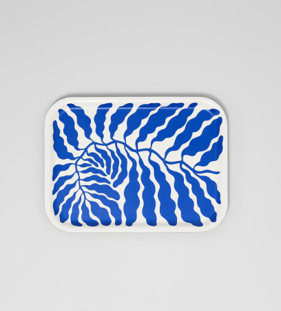 A rectangular birch serving tray by Wrap, showcasing an abstract pattern of bold blue leaves on a white background.