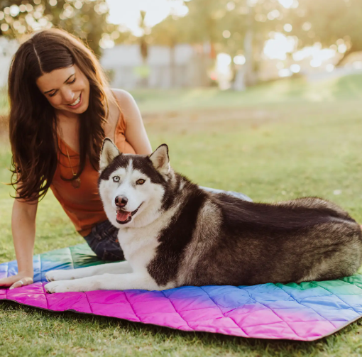 A happy woman and her dog, enjoying the outdoors on the Rainbow Vista Outdoor Picnic Blanket & Tote.