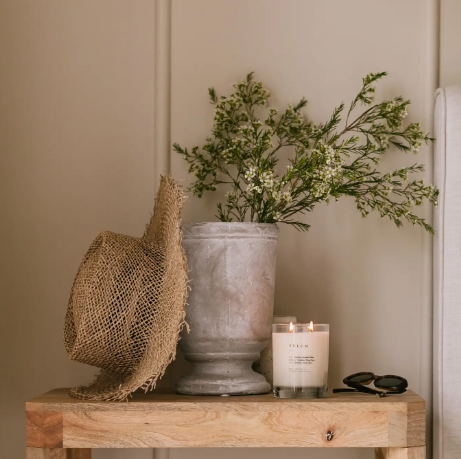 Style your nightstand or accent table with a minimalist double-wick candle next to fresh botanical stems to create a warm, inviting retreat.