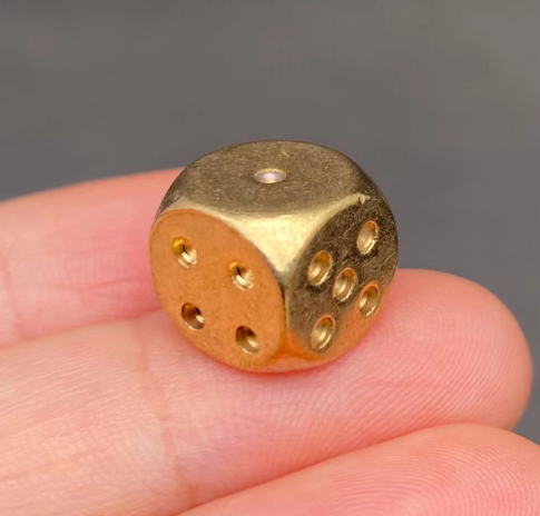 Roll into your next adventure with a luxury solid brass die cradled securely between two fingers to showcase its premium compact size.