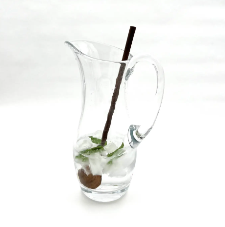 A long, narrow walnut wood spoon resting on the rim of a tall serving container, highlighting its functional design and high-quality craftsmanship.