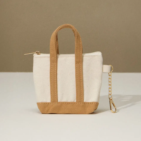 Add a touch of utility and style with the Taupe Mini Canvas Pouch Bag Charm by Sensibling Corp., featuring an attached gold chain clip.