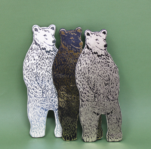 Three Ark Colour Design Bear Magnets in gold, black, and cream, standing upright against a vibrant pink background.