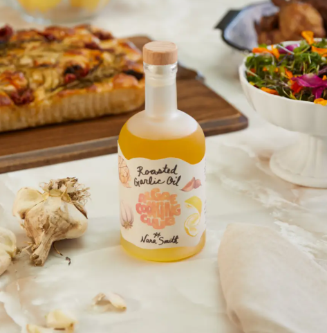 Showcase the elegant glass bottle of Nara's Roasted Garlic Oil by Algae Cooking Club against a warm, neutral background.