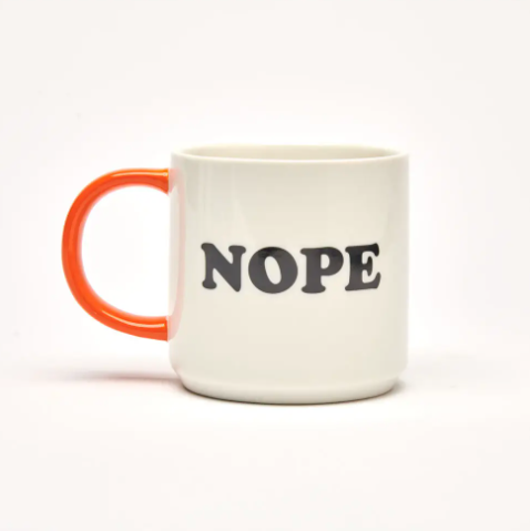 The white ceramic mug with an orange handle, featuring the bold black text "NOPE" on the reverse side.