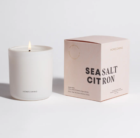 Experience the invigorating glow of the Homecoming Sea Salt Citron Soy Wax Candle, its flickering flame adding a serene and bright ambiance to any setting.