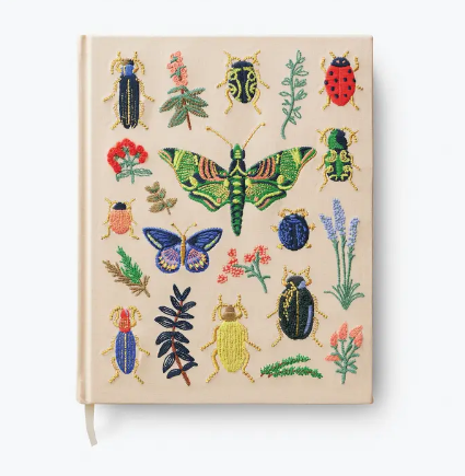 Large cream-colored fabric sketchbook featuring colorful embroidered beetles and bugs with metallic gold accents.