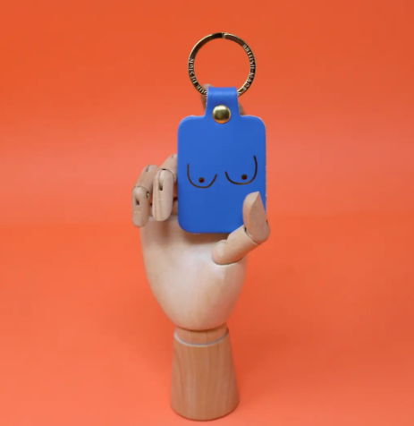 A unique and empowering cornflower leather keyring shaped like a boob, a playful symbol of strength and femininity.