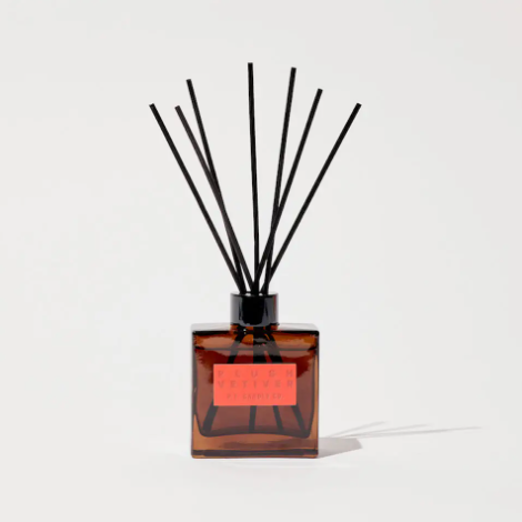 The P.F. Candle Co. Plush Vetiver Hi-Fi Diffuser, showcasing its square amber glass bottle, black reeds, and striking red debossed label, perfect for a chic interior.