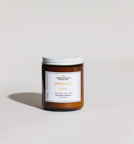 Commonwealth Provisions Grapefruit + Sage candle in an amber jar with a white label.