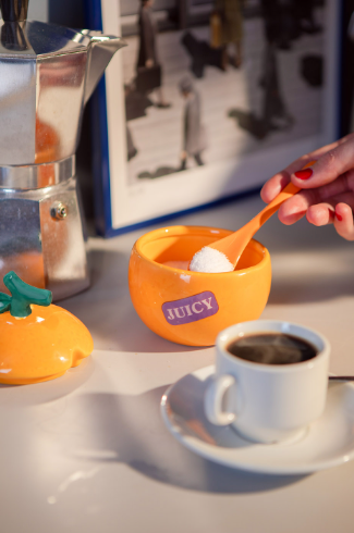 Scoop sugar into your morning coffee with a playful orange fruit-shaped ceramic sugar cellar that includes a matching orange spoon and a convenient built-in lid slot.