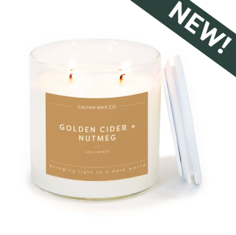Calyan Wax Co.'s Golden Cider + Nutmeg soy candle in a clear glass tumbler with a wooden lid, delivering a cozy, spicy autumn aroma.