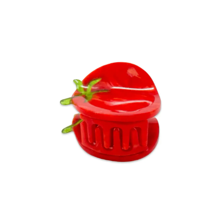 A small, vibrant red tomato-shaped hair clip resting on a surface, highlighting its cute and unique design.