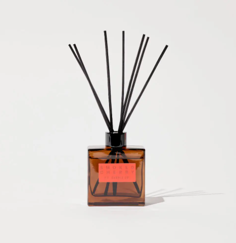 The P.F. Candle Co. Smoked Cherry Hi-Fi Diffuser, showcasing its square amber glass bottle, black reeds, and striking red debossed label, perfect for a chic interior.