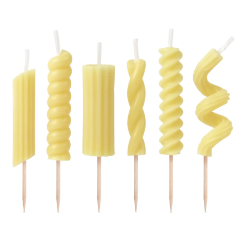 A lineup of the six distinct pasta shapes included in the Pasta Party Noodle Candles set by Fred & Friends, featuring realistic noodle textures and wooden picks.