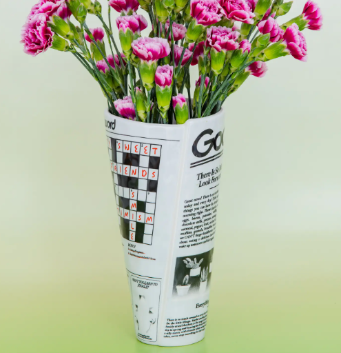 Make a statement with the Ban.do Ceramic Newspaper Vase, elegantly showcasing a bouquet of pink and white flowers, ready to add urban charm to your space.