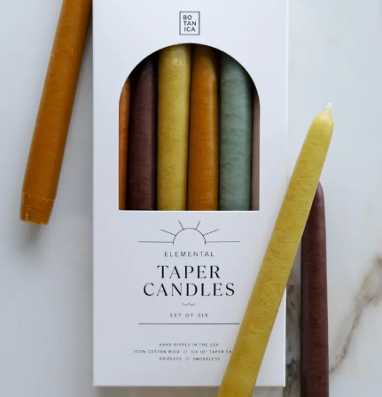 A set of six BOTANICA Earth Collection taper candles featuring a gradient of grounded brown, tan, and olive tones.