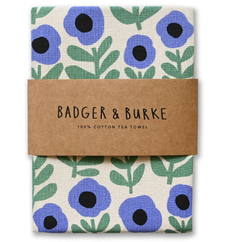 Brighten your kitchen with the Purple Poppy Tea Towel by Badger & Burke, folded neatly with a branded kraft paper band.