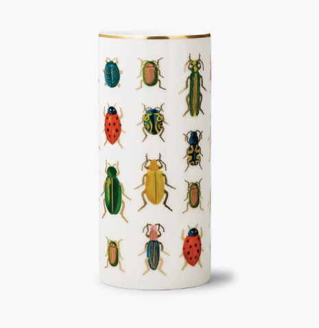 A white porcelain cylinder vase by Rifle Paper Co. featuring colorful beetle and bug illustrations with a metallic gold rim.