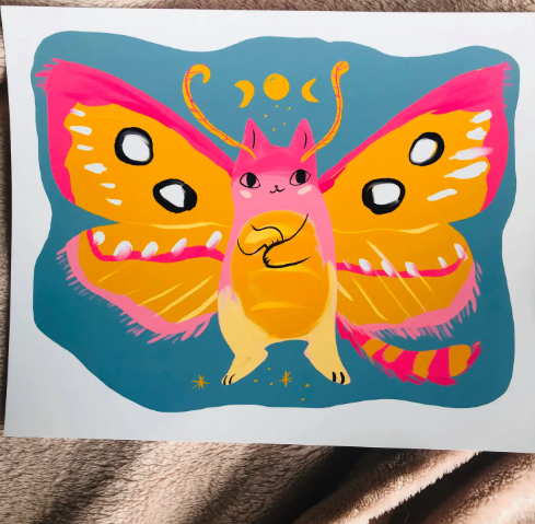A vibrant art print featuring the Pink Star Moth Cat with glowing pink and orange wings against a blue background, ready to bring bold color to your home decor.
