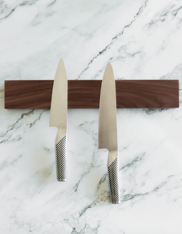 Upgrade your kitchen with this elegant solid walnut magnetic knife block, securely holding two chef knives against a stunning marble backsplash.