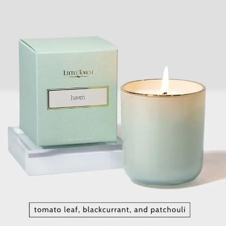 The Haven candle by Little Torch, displayed with its light mint-green vessel and box, lit to create a fresh, tranquil atmosphere reminiscent of a sunlit meadow.