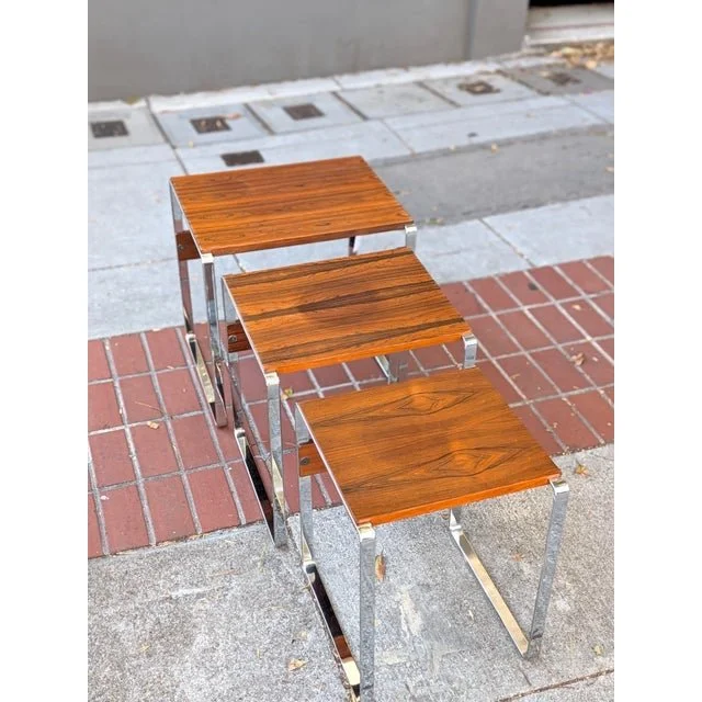 Vintage rosewood and chrome nesting tables, three pulled apart on a brick sidewalk