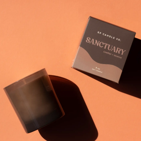 A deep taupe glass soy candle in a matching box, showcasing its sleek and sophisticated packaging.