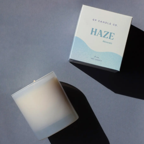 A pastel blue glass soy candle in a matching box, showcasing its stylish and modern packaging.