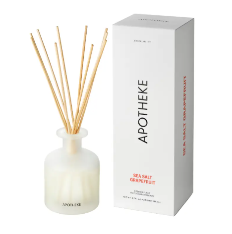 APOTHEKE Sea Salt Grapefruit Reed Diffuser set featuring a frosted translucent glass bottle filled with golden oil and a bundle of natural rattan reeds.