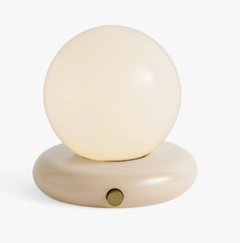 Co.House Designs Valencia Portable Table Lamp in ivory showcasing its minimalist silhouette and warm glowing bulb.