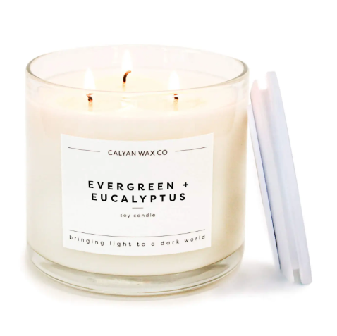 Calyan Wax Co.'s Evergreen+Eucalyptus 3-Wick Soy Candle with a wooden lid, delivering a crisp, long-lasting scent and supporting the fight against human trafficking.