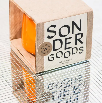 A minimalist Sonder Goods soy candle in an amber glass jar, featuring a destination-inspired scent like White River.