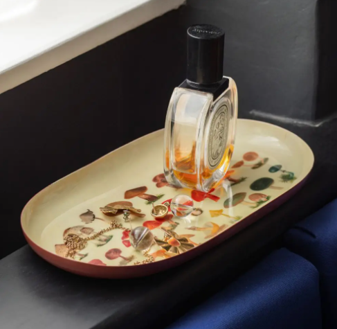 Close up of the oval enamel tray from Roomytown Inc featuring vintage fungi illustrations used to hold jewelry and perfume.