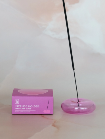 A handblown Orchid Translucent glass bubble incense holder by BOTANICA with a minimalist spherical design.