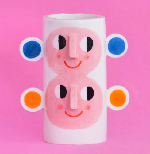 The Ana Seixas Double Face with Orange & Blue Ears Vase, a unique ceramic piece with two abstract faces, orange and blue ear-like protrusions and a glossy finish.