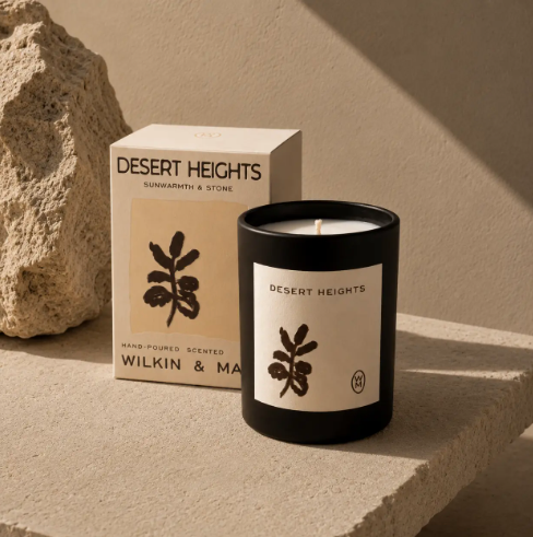 The Desert Heights Luxury Candle by Wilkin & May sits proudly beside its minimalist decorative box on a textured stone surface.
