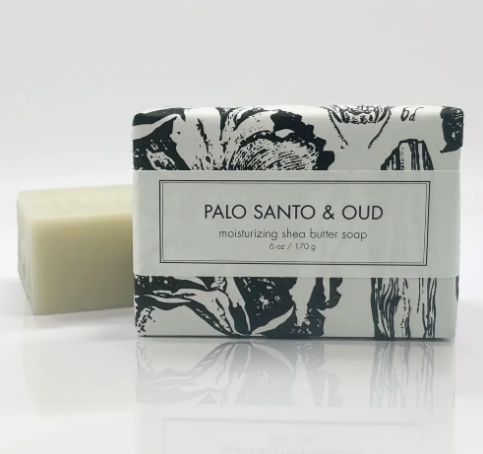 Elevate your daily ritual with the luxurious Palo Santo & Oud Shea Butter Soap by Formulary 55, featuring an elegant botanical-wrapped bar alongside a rich, logo-embossed bar.