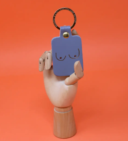 A unique and empowering lilac grey leather keyring shaped like a boob, a playful symbol of strength and femininity.